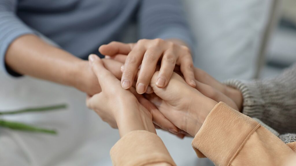 Individuals holding hands and offering support during West Austin Sober Living.