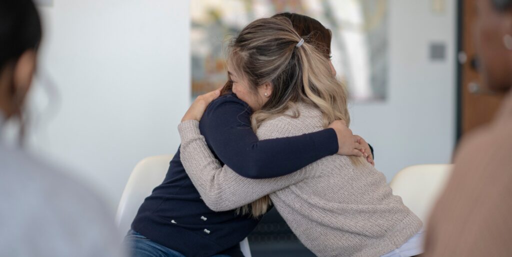 Two women offering mutual support during the Spicewood at BullCreek sober living program.